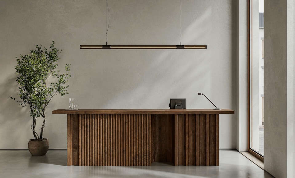 An empty reception desk in fluted timber, a plant beside it, in soft daylight.
